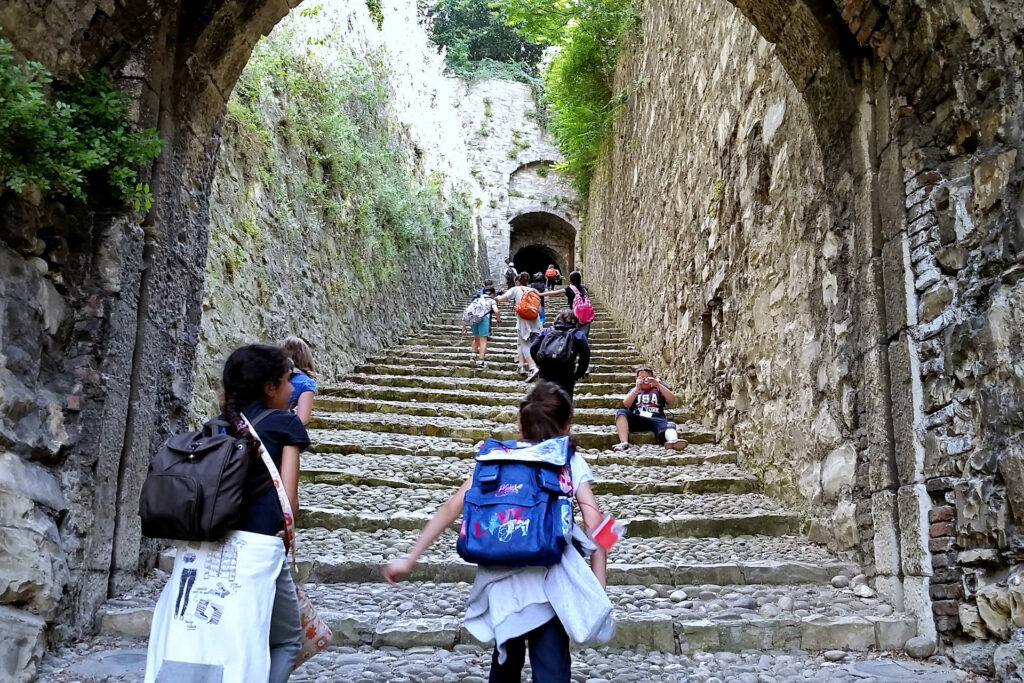 Fotografia di un gruppo di bambini che corrono risalendo la strada del soccorso del Castello di Brescia