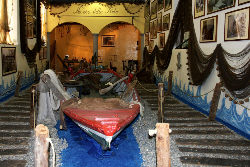 Fotografia di una stanza del Museo della Rete di Porto Siviano con al centro un naèt, imbarcazione tipica del lago d'Iseo